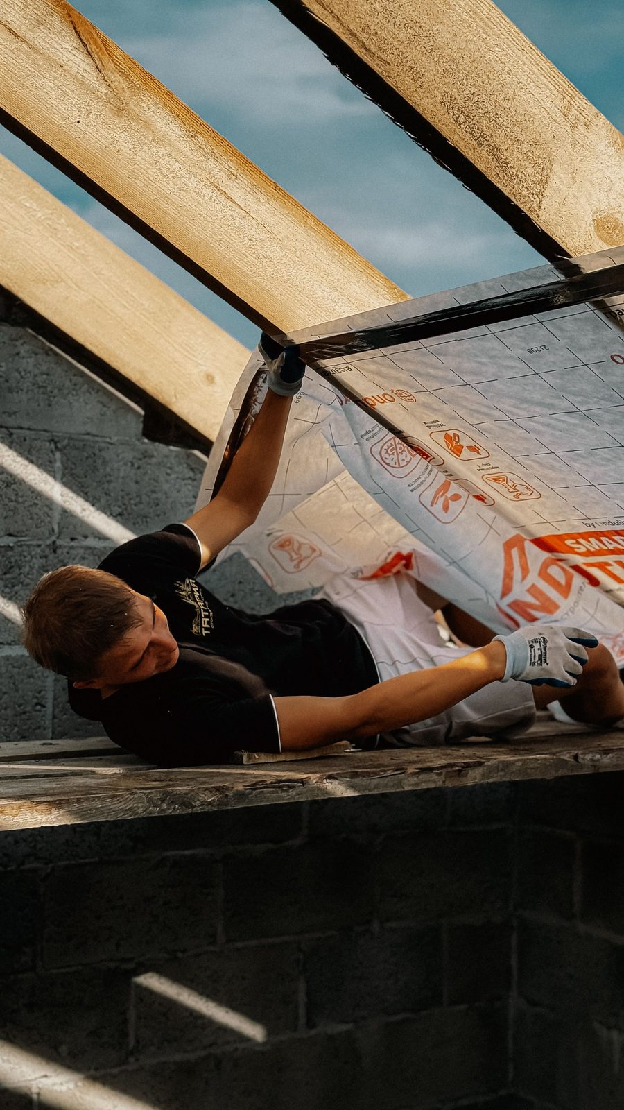 Worker installing an insulation membrane on a roof frame