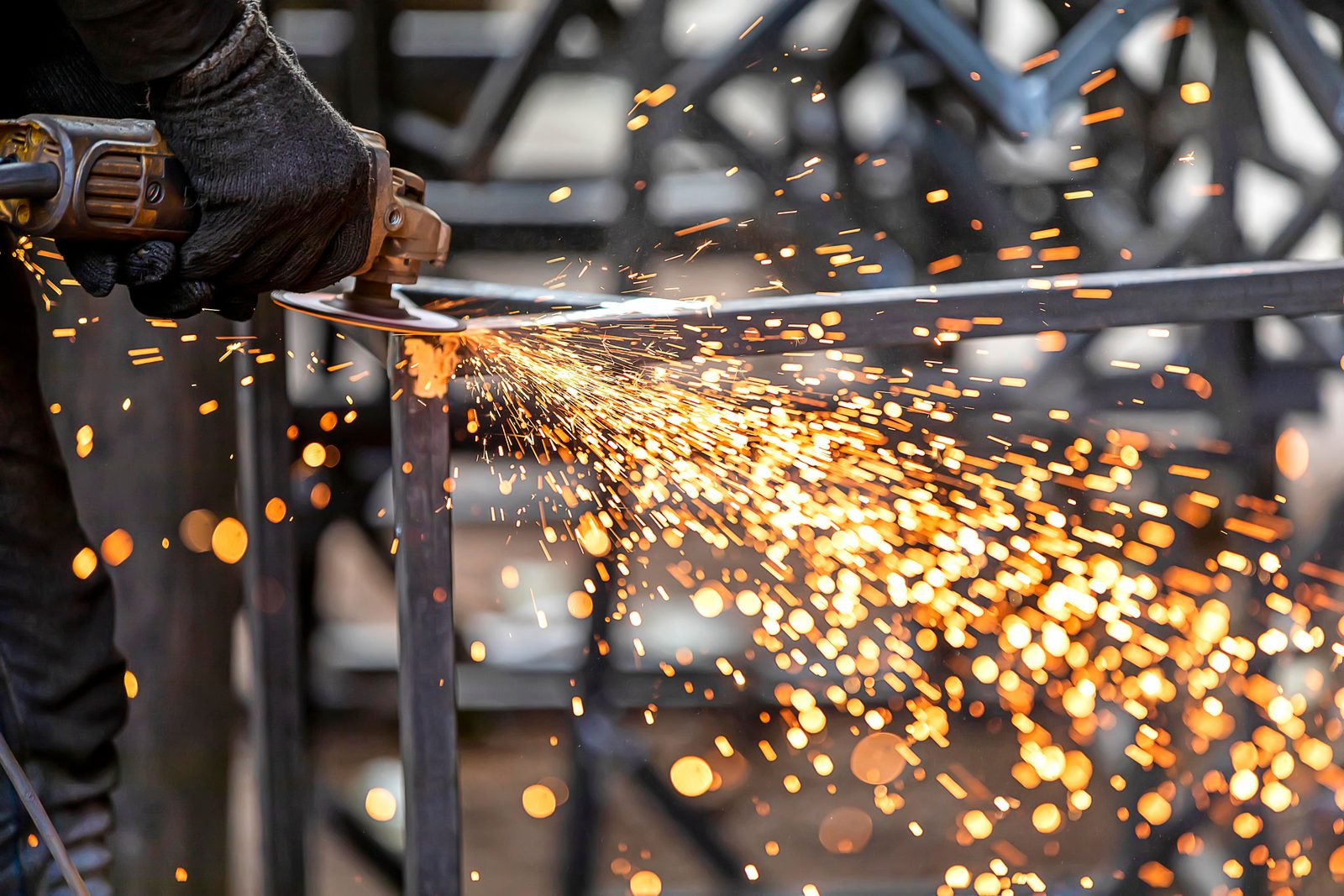 Worker grinding metal in a workshop, sparks flying from the angle grinder
